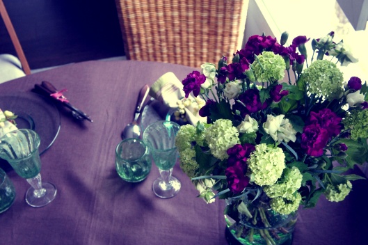 Sur la table, un beau bouquet d’œillets prune et de fleurs vertes...